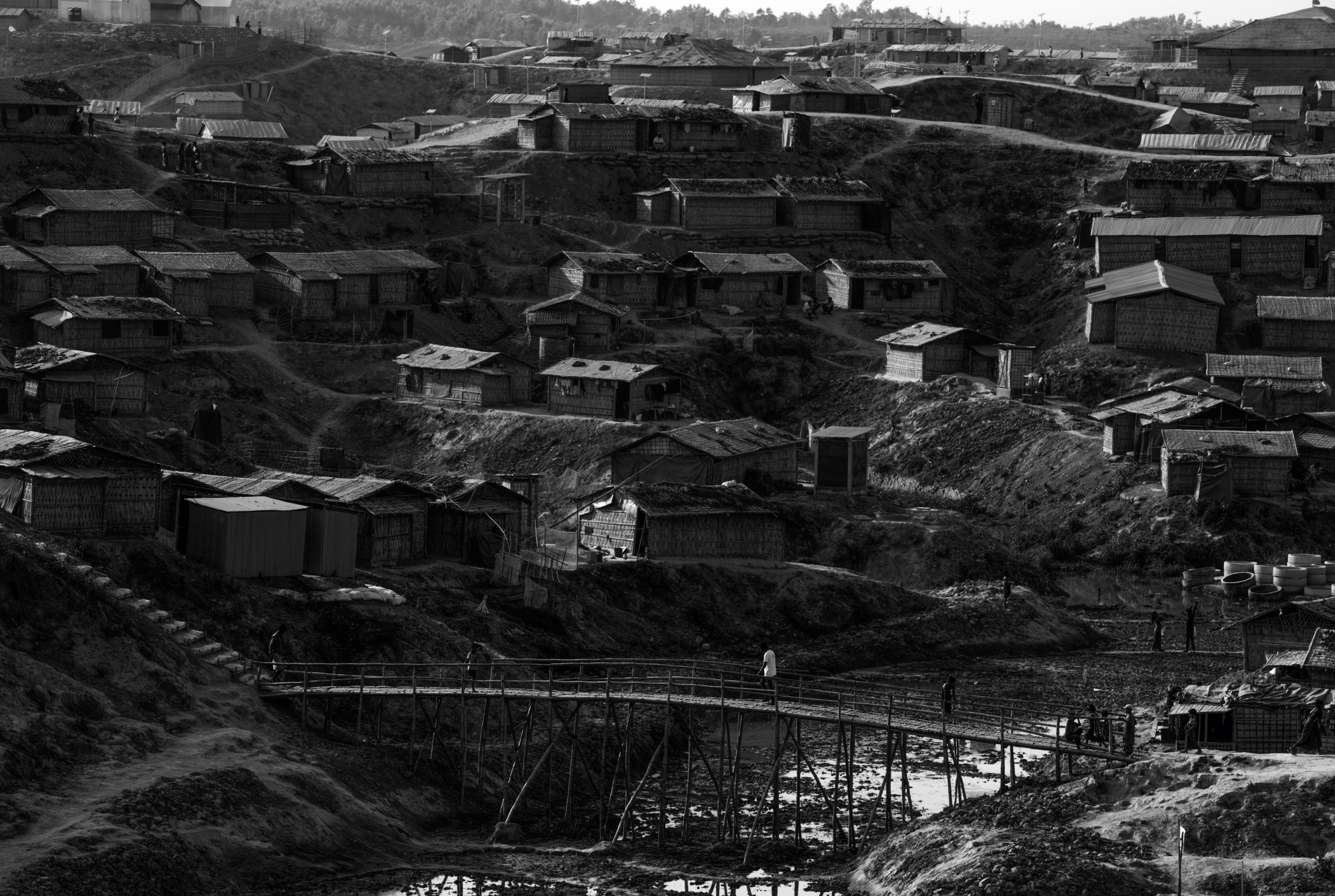 Bangladesh, Cox's Bazaar.
Shelters in the Kutupalong Rohingya refugee camp. .Over 650,000 Rohingya have crossed the border to Bangladesh since August last year, fleeing the violence at Rakhine State when their villages were attacked and many worry that they will face further reprisals if they return to Myanmar. The refugee camps in Bangladesh no longer seem temporary as thousands of tents made of plastic and bamboo spread across the undulating terrain and long wooden bridges connect parts of the camps divided by water. Existing camps such as Nayapara and Kutupalong have swelled to accommodate the new arrivals since the Myanmar military began its campaign in late August while the Rohingya queue for hours to get rations due to little access to clean water, health care or food and the refugee camps turn into mud-baths whenever it rains. International aid groups and health workers have estimated at least 6,700 Rohingya had met with violent deaths and warn of potential outbreaks of cholera and other preventable diseases due to squalid conditions.