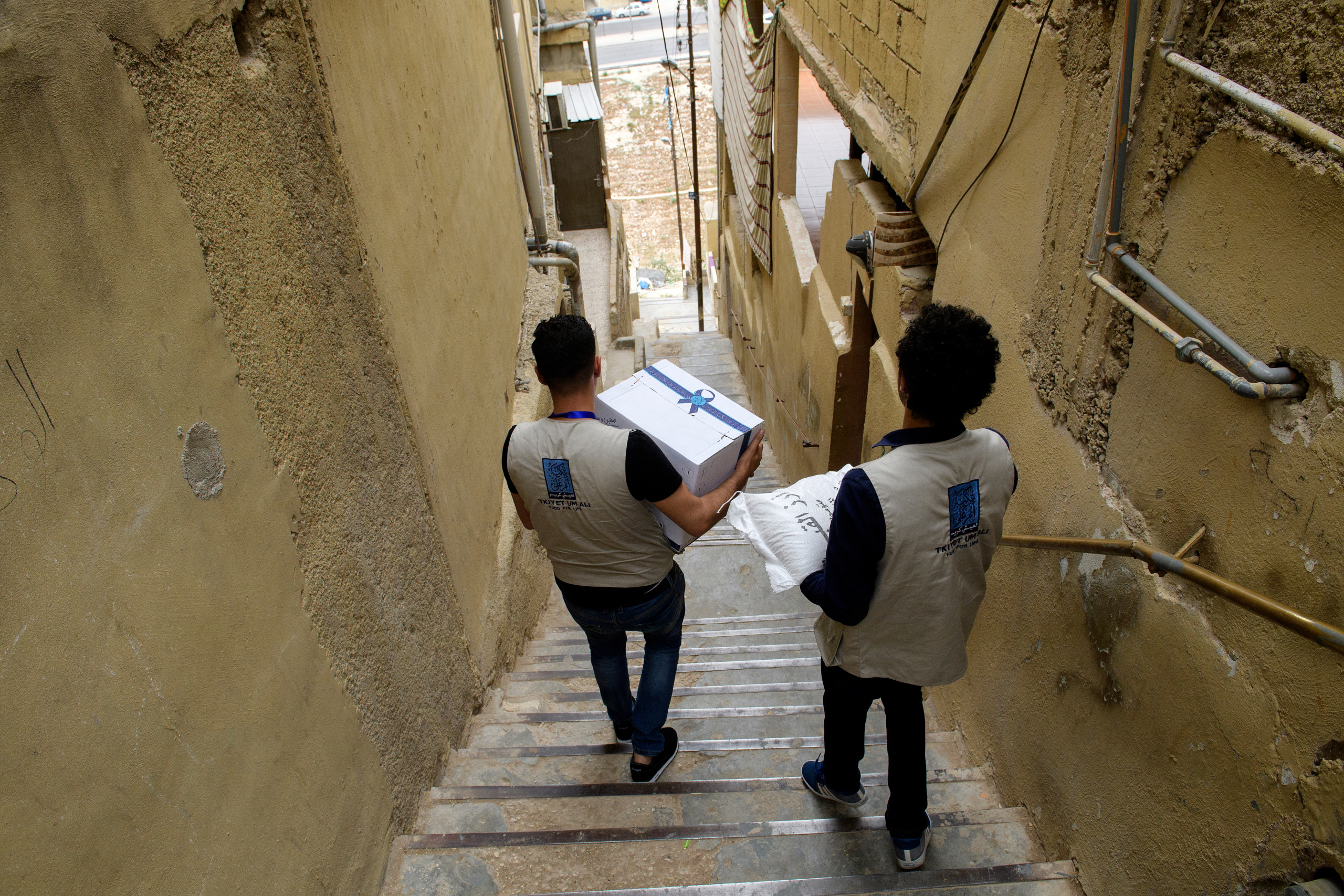 Social workers bring a food package to benificiaries of TUA.
A food parcel will be delivered to an endorsed family according to the value of the parcel which in return depends on the number of family members. The food Parcel contains 22 food commodities enough to prepare three meals to the family throughout the month. Currently 30,000 families receive food parcels on monthly basis.
Tkiyet Um Ali (TUA) was founded in 2003 by Her Royal Highness Princess Haya Bint Al-Hussein to represent the first non-governmental organization that seeks to eradicate hunger by providing sustainable food aid through distributing food parcels and serving hot meals at its premises to Jordan’s most unprivileged. Originally conceptualized by Her Late Majesty Queen Alia more than 40 years ago, TUA is inspired by the Islamic concept of providing food for the underprivileged and assuming social responsibility for them. Through this project, Her Royal Highness Princess Haya Bint Al-Hussein continues her mother’s short lived, yet rich legacy.